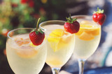Three cocktail glasses with citrus and strawberries