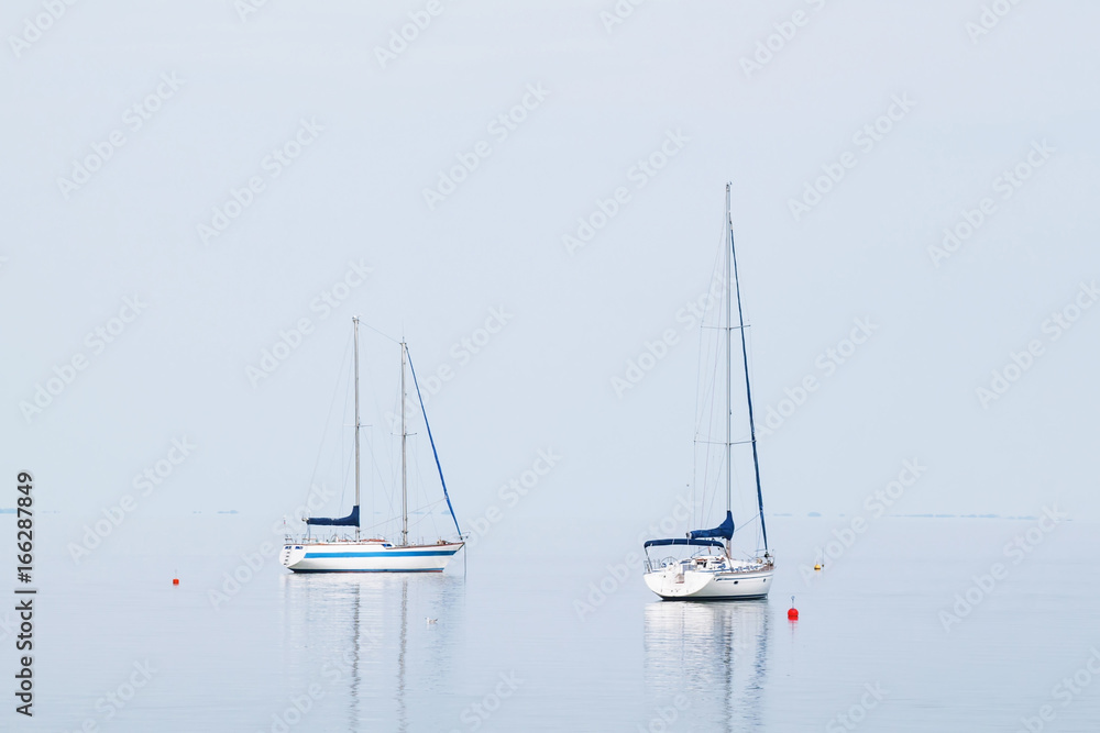 Sailing yacht in the blue sea with sails down, summer landscape