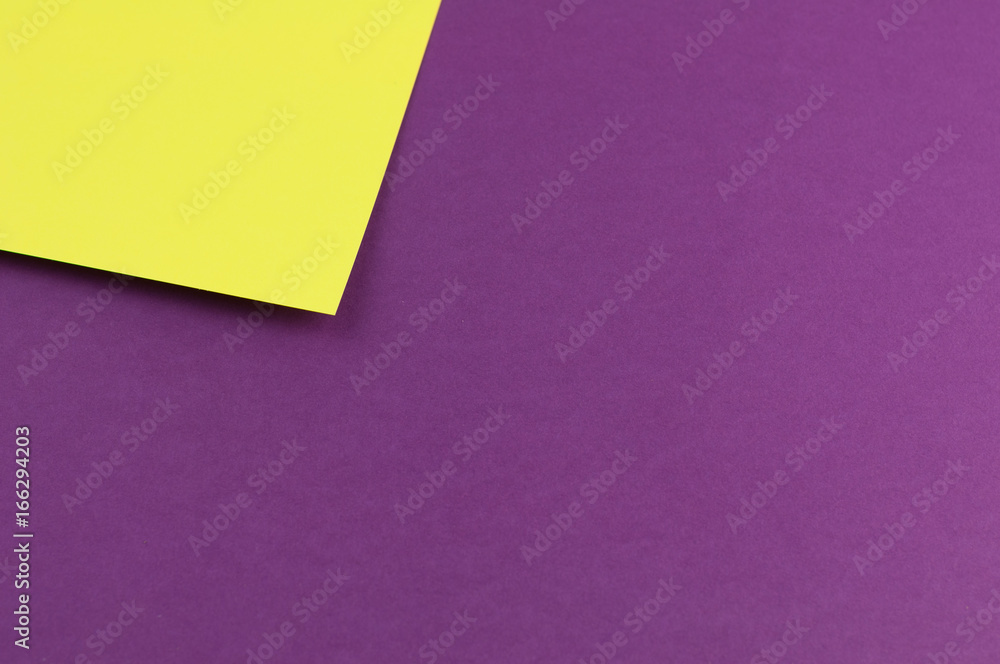 Corner of yellow paper sheet on violet paper background Corner of yellow paper sheet on violet paper background