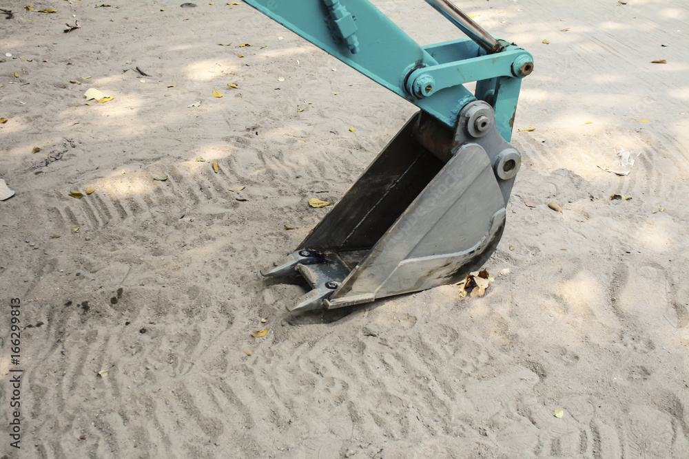 Close up image of backhoe bucket  on the sand