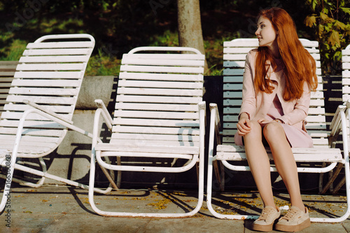 Portrait of a pretty red-haired teenage girl. She smiles and dreams. The sun beautifully illuminates his hair. 4K slow motion video