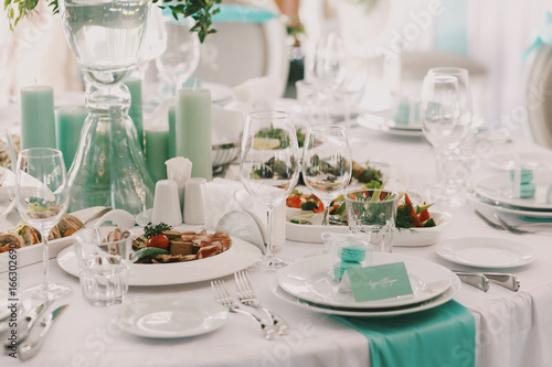 Dinner table served wiht white plates and mint candles © IVASHstudio