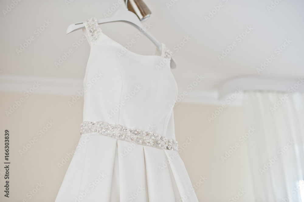 Wedding dress hanging on the rack in the room. Wedding dress hanging on the rack in the room.