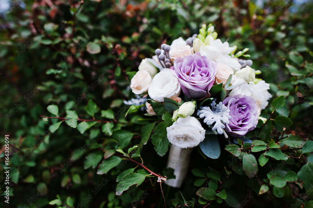Fototapeta premium Close-up photo of a fantastic wedding bouquet laying on the bushes.