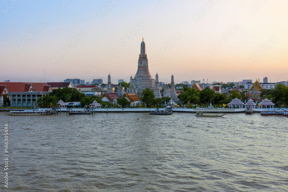 Wonderful ancient Pagoda of Wat Arun one of the most beautiful archaeological site view from Chao Phraya River side in twilight time from Bangkok, Thailand. (With warm sunlight effect) 
