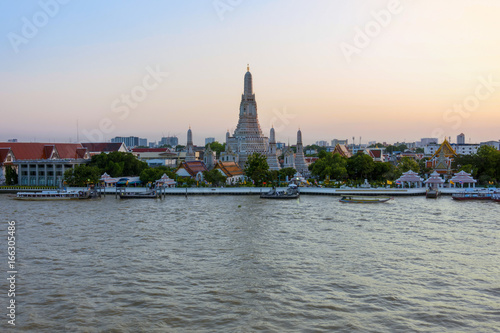Wonderful ancient Pagoda of Wat Arun one of the most beautiful archaeological site view from Chao Phraya River side in twilight time from Bangkok, Thailand. (With warm sunlight effect) 