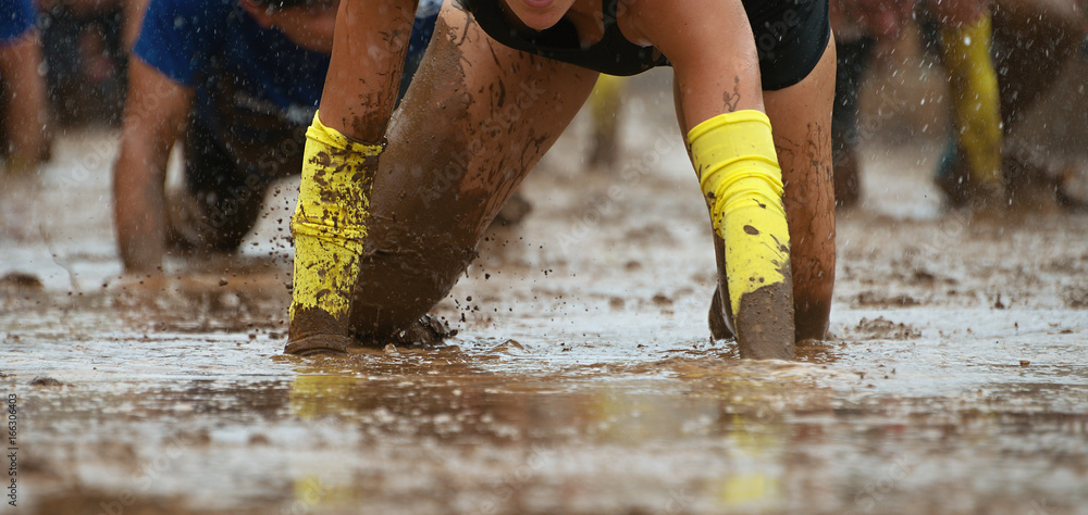 Mud race runners.Crawling,passing under a barbed wire obstacles during ...