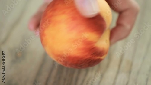 Slicing orgenic peach on wood cutting board photo