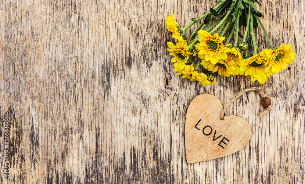 Naklejka premium Summer yellow flowers and heart on a wooden background. Copy space