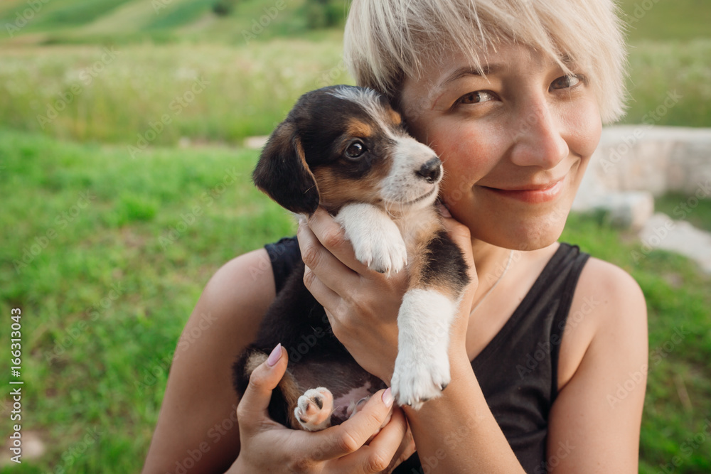 Blonde woman plays with a puppy on green lawn Blonde woman plays with a puppy on green lawn