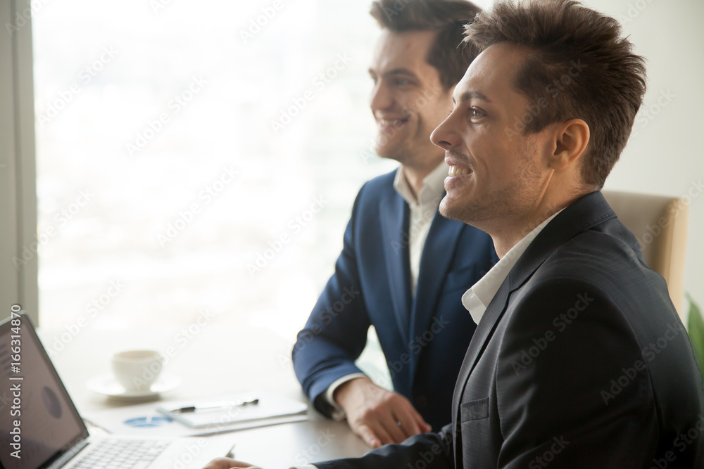Smiling attentive businessmen attending conference meeting, listening to speaker at presentation, audience of financial training or business seminar, accounting courses, side view, copy space