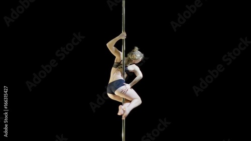 Beautiful girl in a black swimsuit demonstrates the elements pole dance