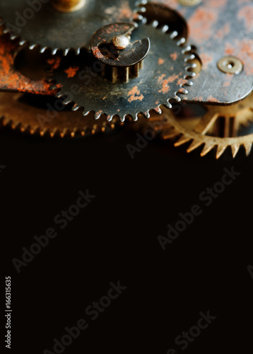 Cogs gears wheels mechanism on black background. Vintage clockwork parts closeup. Copy space, vertical photo