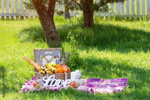 Picnic setting for a couple in love. Carpet with picnic basket in the garden, word LOVE on the grass. photo