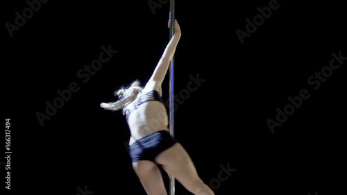 Blonde girl shows the elements of the dance on the pylon
