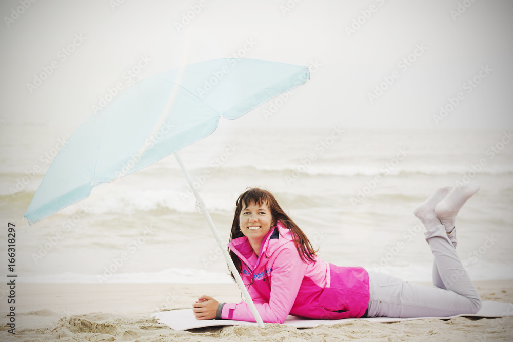 Photo of beautiful girl in a coat lying on a sandy beach