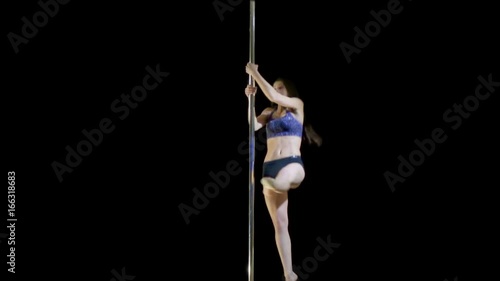 Young beautiful girl performs complex movements on the pylon