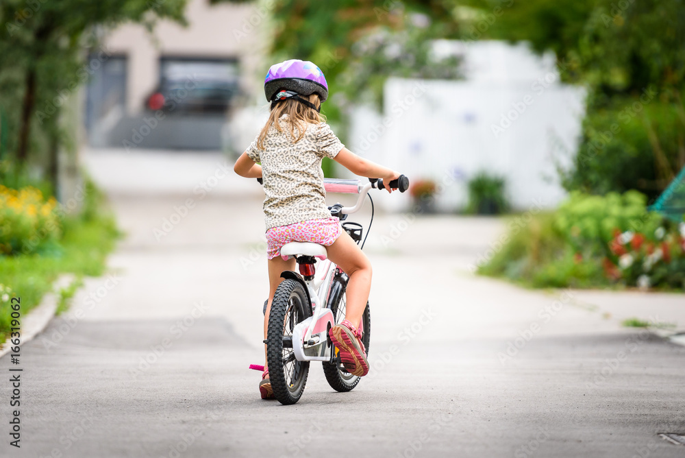 Children learning to drive a bicycle on a driveway outside. Children learning to drive a bicycle on a driveway outside.