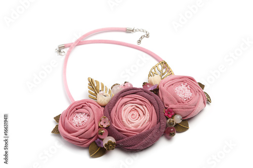 Handmade necklace in the form of three fabric flowers with metal leaves on a white background photo