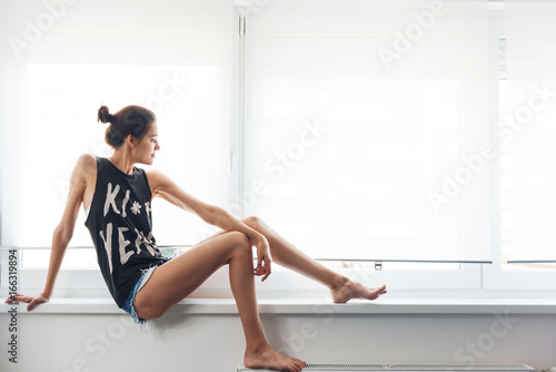 Cute, young woman sitting by the window 