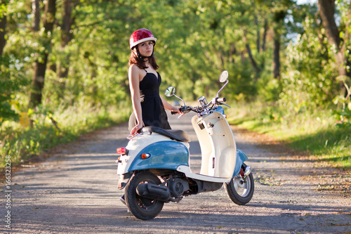 A girl with a scooter on a country road