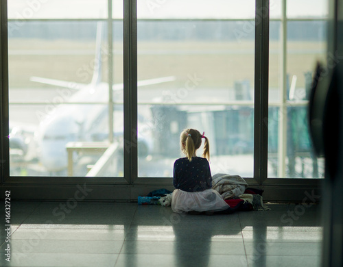 The little girl sits near a big window at the airport. Free Download The little girl sits near a big window at the airport. - GFXLoad