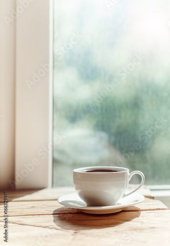 cup of coffee on old wooden desk. Simple workspace or coffee break in morning/ selective focus