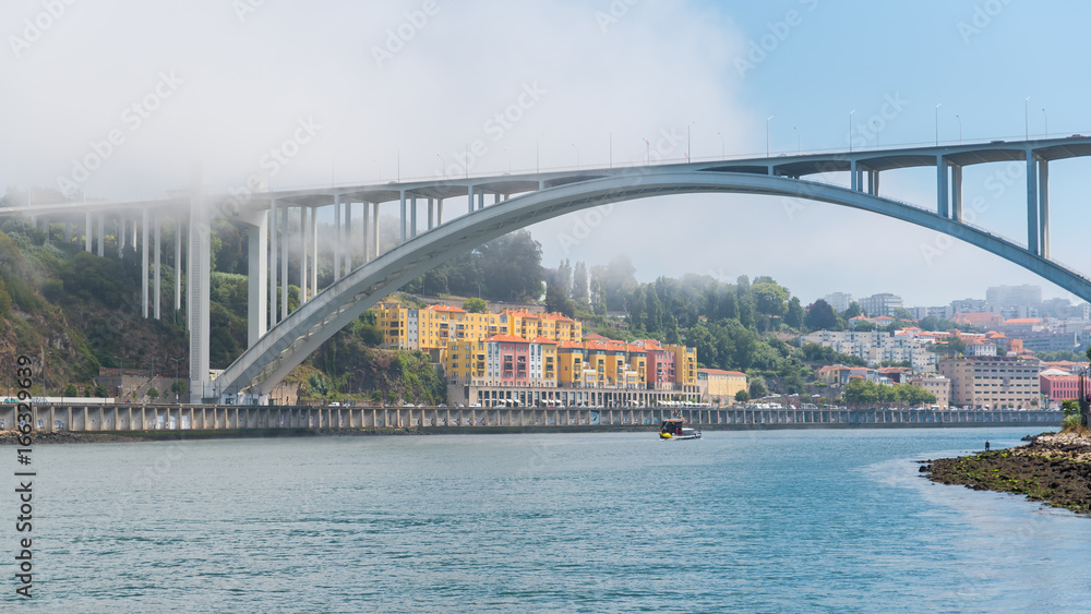 Porto in Portugal, Arrabida bridge, view of the Douro river in the mist, with a traditional boat
