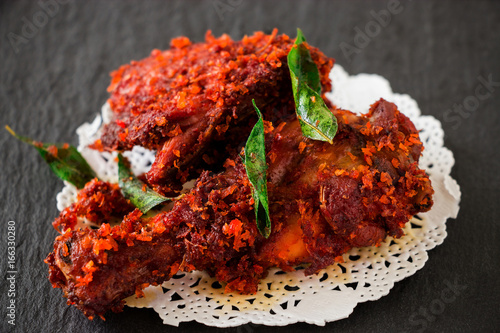 Authentic Indian Chicken fry with spices, curry leaf and coconut - payyoli chicken fry. Famous Kerala course. Copy space. Dark background