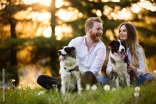 Sticker Beautiful couple cuddling and walking dogs outdoors