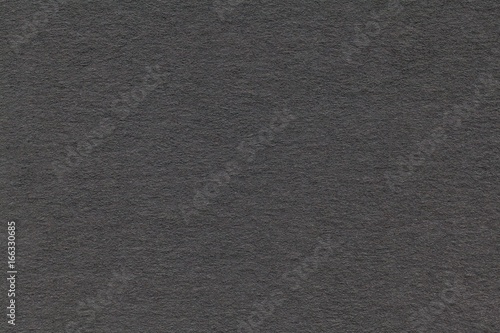 Texture of old gray paper closeup. Structure of a dense cardboard. The black background.