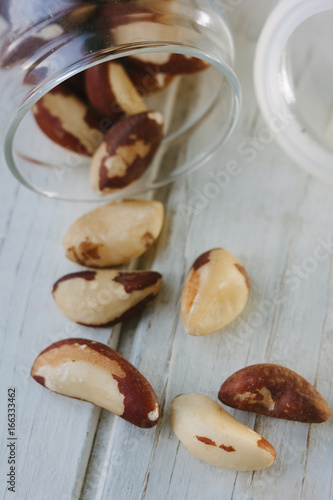 Brazil nuts and glass bottle over the white table