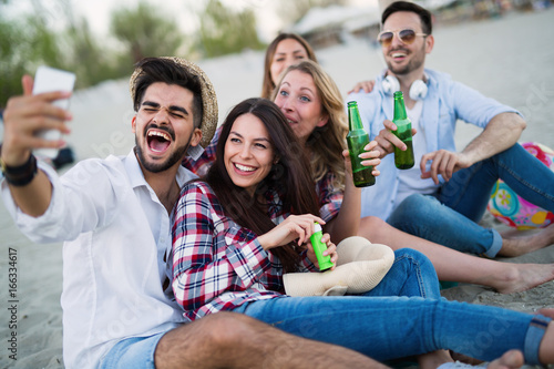 Friends partying and having fun on beach at summer