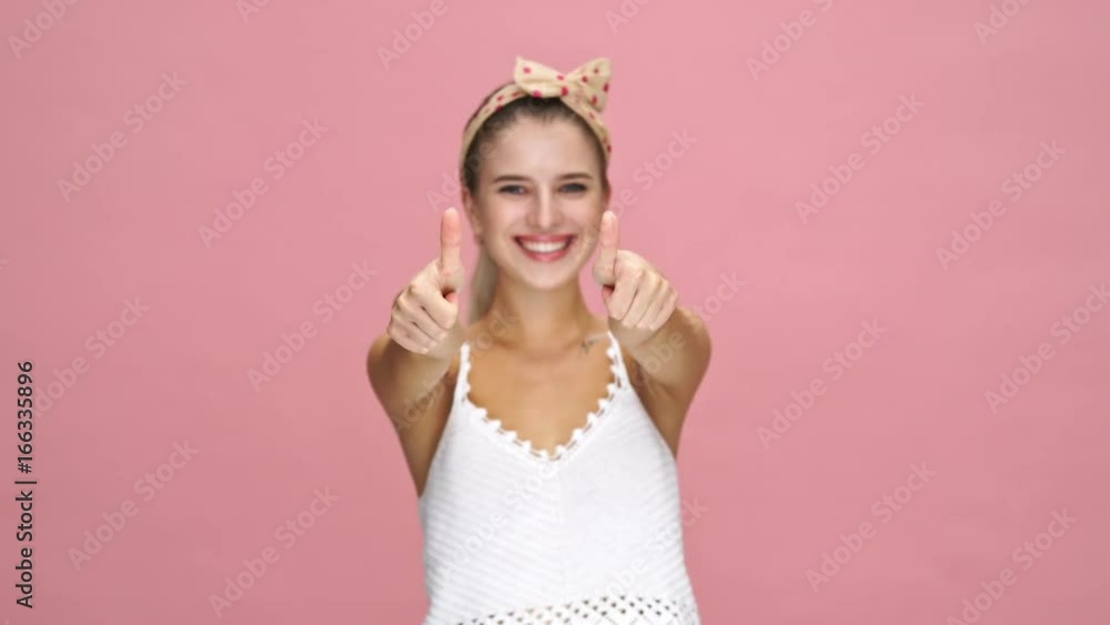 Young happy caucasian lady smiling and showing thumbs up gesture over pink background Young happy caucasian lady smiling and showing thumbs up gesture over pink background