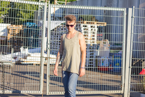 Young man in sunglasses posing on urban background, hipster male model  