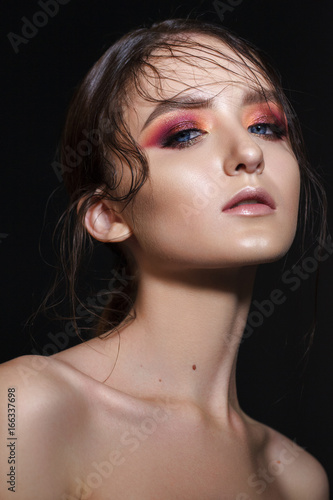 Portrait of beautiful young model with professional makeup, perfect skin, wet hairdo. Trendy colorful smoky eyes.