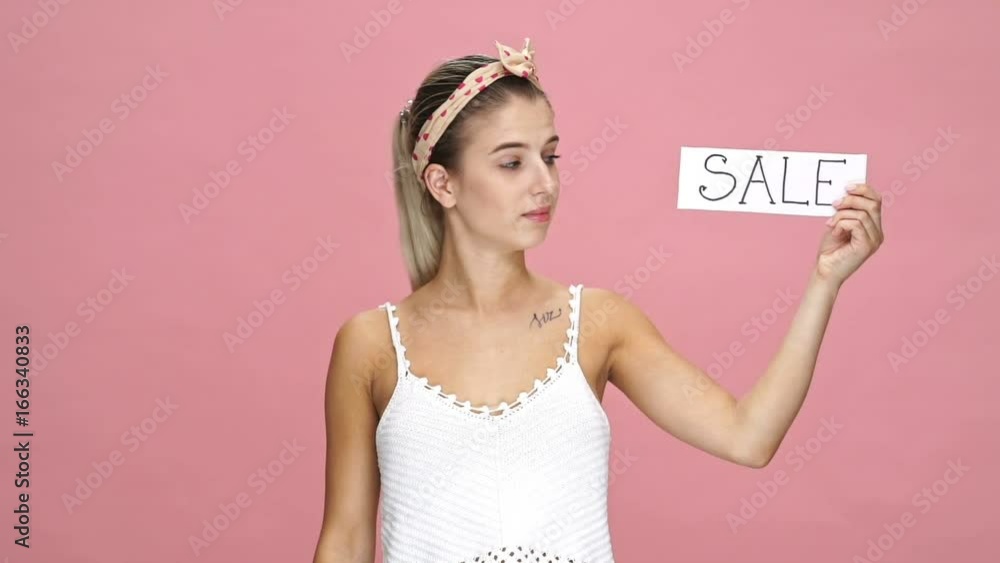 Young caucasian woman looking camera holding shopping bags over pink background happy because of sale Young caucasian woman looking camera holding shopping bags over pink background happy because of sale