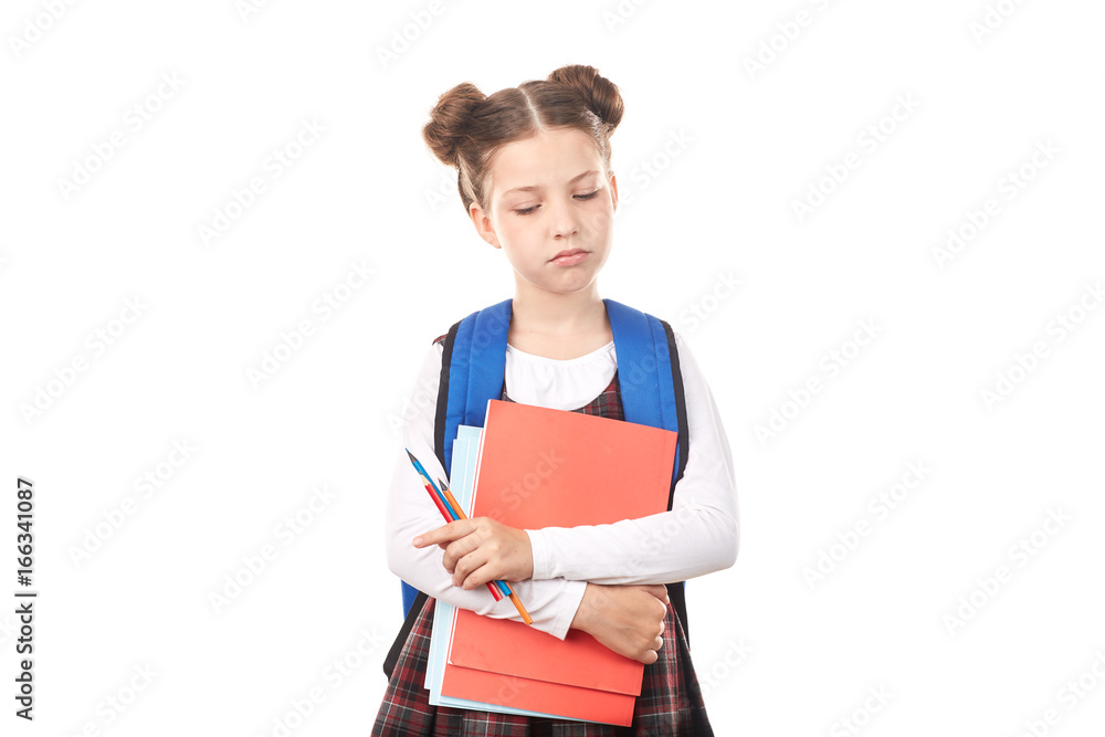 Portrait of girl in school uniform with backpack holding textbooks and pencils and thinking sadly against white background Portrait of girl in school uniform with backpack holding textbooks and pencils and thinking sadly against white background
