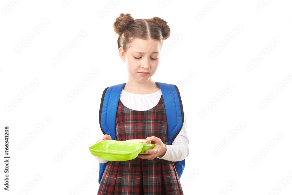Portrait of cute girl in school uniform standing with lunchbox against white background