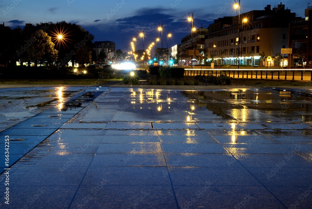Wet urban square after summer rain and night street lights