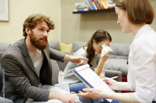Foto Portrait of young family quarreling and arguing in doctors office at couples cou