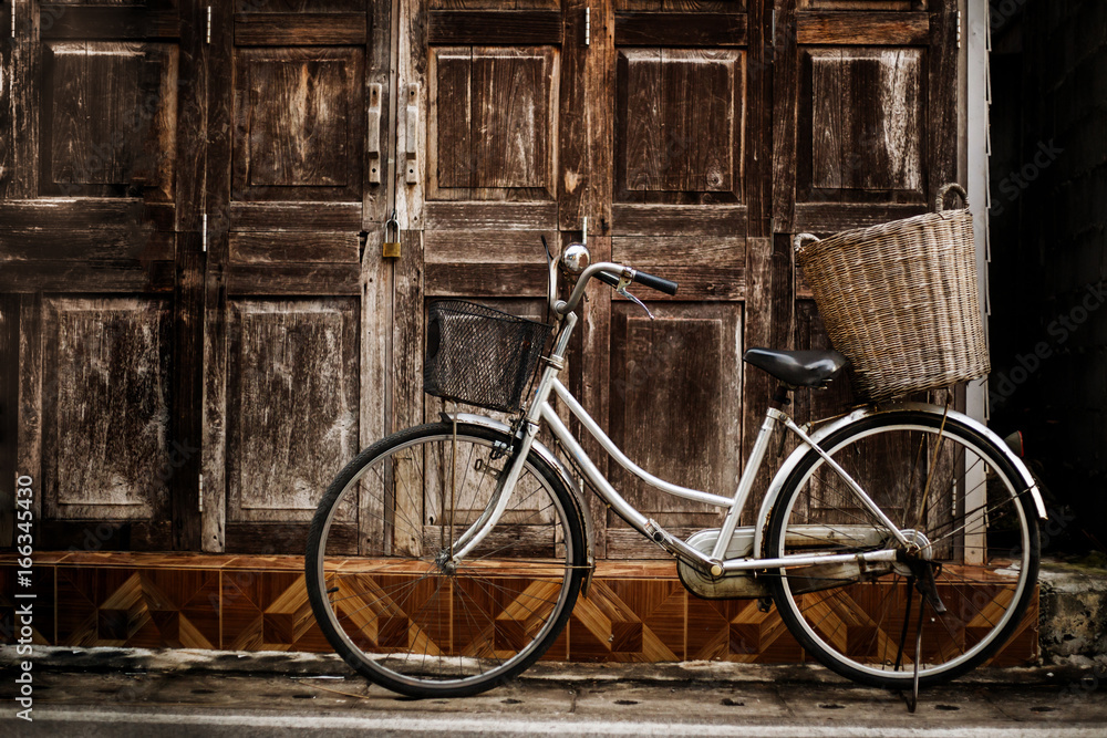 Old bicycle parked in the old wooden wall.