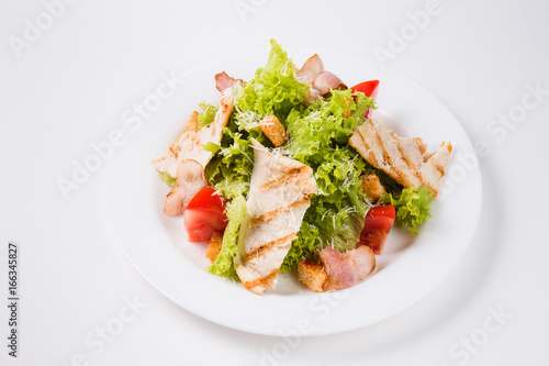 salad with bacon, tomatoes and croutons on a white plate
