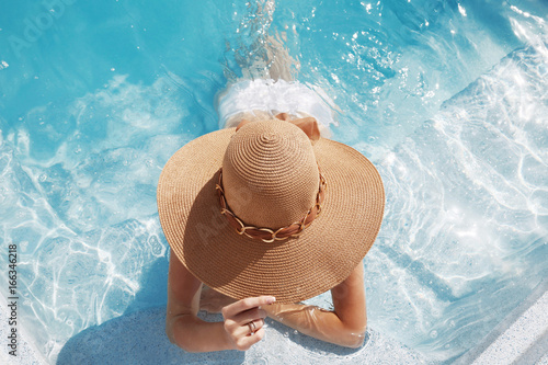 Woman in beach hat enjoying in swimming pool on Tropical Resort. Exotic Paradise. Travel, Tourism and Vacations Concept.