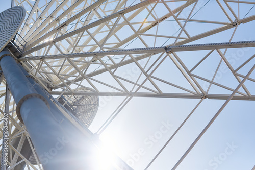 Low angle closeup of huge modern Ferris wheel against blue sky in amusement park