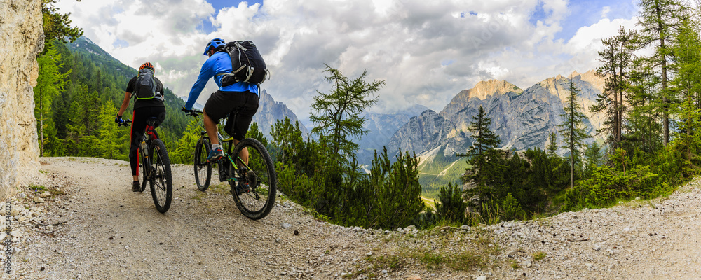 Fototapeta premium Mountain biking couple with bikes on track, Cortina d'Ampezzo, Dolomites, Italy