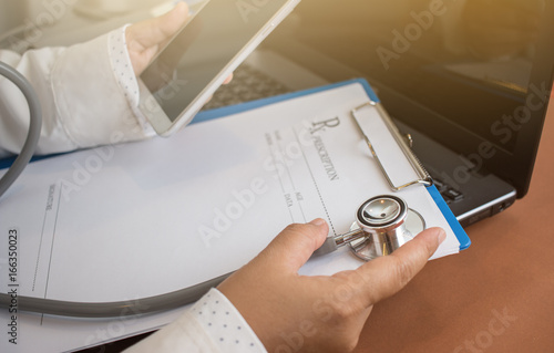 Doctor using Stethoscope on prescription clipboard and Doctor working an Laptop computer and smart phone on desk in hospital, Healthcare and medical concept, selective focus