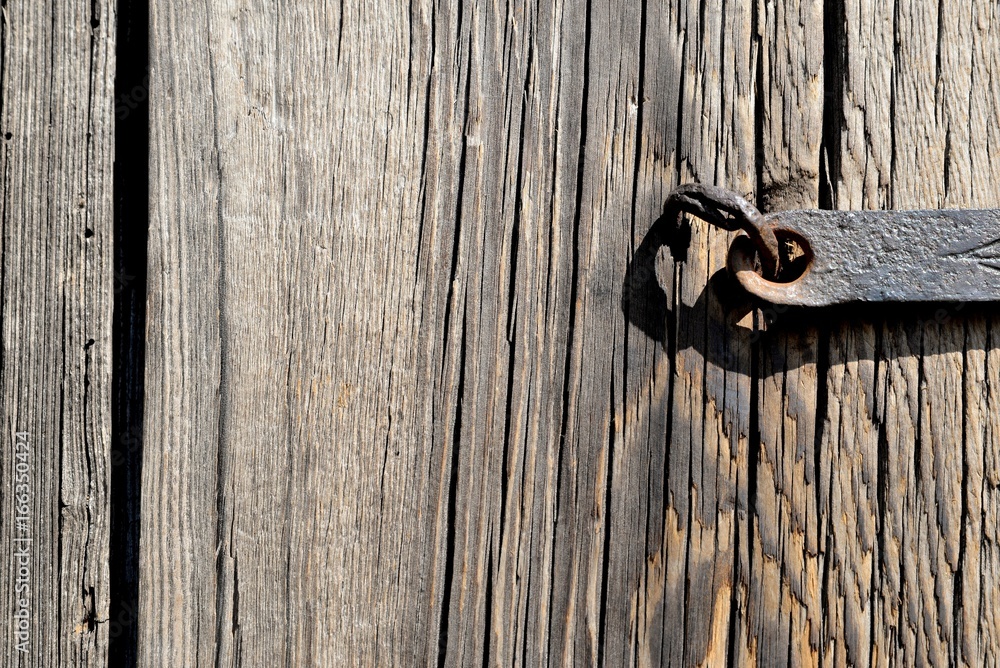 A fragment of an old wooden door closed on a steel skeleton