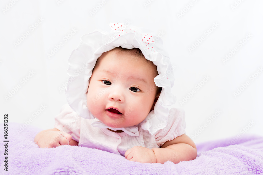 Portrait of a little adorable infant baby girl lying on the tummy on the pillow with head band Portrait of a little adorable infant baby girl lying on the tummy on the pillow with head band