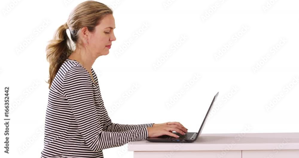 Profile of woman seated at table, working on laptop in studio with copyspace Profile of woman seated at table, working on laptop in studio with copyspace